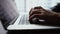 Close-up of hands of unrecognizable businessman typing on laptop keyboard working at office desk