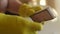 Close up hands of unrecognizable man in yellow gloves cleaning dusty dirty air filter of robot vacuum cleaner with brush