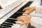 Close-up hands of unrecognizable musician female pianist playing gentle music on white classical piano in light