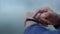 Close-up hands of unrecognizable tired sportsman wearing sportswear standing outdoors resting after workout and using