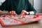 Close-up hands of unrecognizable young woman gluing envelopes on board with gifts for children making Christmas advent