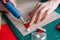 Close-up hands of unrecognizable young woman gluing envelopes on board with gifts for children making Christmas advent