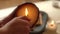 Close-up hands of unrecognizable young woman lighting handmade aromatic candle with lighter in bathroom.