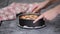 Close up of the hands of a woman removing the mold from the cheesecake.