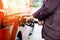 Close-up of hands of woman at self-service gas station, hold fuel nozzle and refuel the car with petrol, diesel, gas