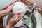 Close up hands of woman washing dishes in kitchen. Cleaning chores