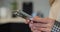 Close-up of hands of woman writes a text message on smartphone in the living room at home. Online shopping in social