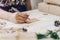 Close up of hands woman writing empty wishlist and christmas card on wooden table with xmas decoration