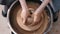 Close up of hands working clay on potter\'s wheel. Potter shapes the clay product with pottery tools on the