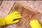 Close up Hands in yellow household gloves remove grease from a dirty electric grill using a sponge and a special spray. Drops of