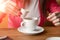 Close-up, hands of a young girl, pours cream or milk into coffee in a cafe on a wooden table