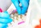 Close-up hands of young woman doctor anesthesiologist dressed in pink gown, blue gloves prepares solution for anesthesia