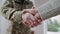 Close-up handshake of middle aged soldier in camouflage and young Caucasian man. Unrecognizable military father and