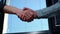 Close-up handshaking of two Caucasian business men colleagues on background of window in sunny day.