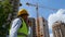 Close up of handsome male worker in hard hat talking in walkie-talkie standing at construction site on street outdoor