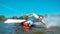 CLOSE UP: Handsome man wakeboarding does a hand drag and splashes water.