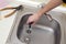 Close-up of handsome plumber hands repairing drain of kitchen sink