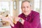 Close up of handsome senior man at home amazed and smiling to the camera while presenting with hand and pointing with finger