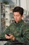 Close up of a handsome young soldier sitting on wheel chair using his cellphone, in a blurred background