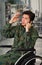 Close up of a handsome young soldier sitting on wheel chair using his cellphone, wearing military uniform in a blurred
