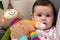 Close-up of happy baby girl playing with cute colourful teddy