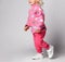 Close-up of happy baby kid girl in pink warm fleece clothing with heart print pattern running, having fun