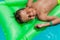 Close-up of happy boy relaxing on green mattress