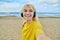 Close-up of happy face of teenage blonde in headphones on the beach.