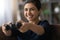 Close up happy Indian woman playing video game, holding controller