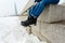 Close-up of a happy and loving couple foot traveler sitting on the granite waterfront. A pair in winter shoes and warm sweaters an