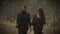 Close up of happy man and woman together walking on the path in the forest. Smiling couple are strolling among the