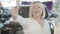 Close-up of happy mature caucasian woman bragging car keys in showroom. Excited senior blond lady showing keys at camera