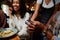 Close-up of happy multiracial friends in casual clothing paying waitress for dinner at restaurant