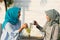 Close up happy shot two hijab women drinking tea in front of the house and smiling