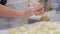 Close up of the happy smiled grandmother and grandson kneading a dough together. Slow motion of an elderly woman and
