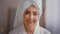 Close up happy smiling attractive senior Caucasian mature grandma 60s middle-aged woman wearing bathrobe and white towel