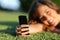 Close up of a happy teen girl hand using a smart phone on the grass