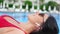 Close-up happy woman in red bikini sunbathing shaking head listening music in wireless earphones