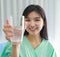 Close up of happy young inpatient woman  who is getting well from her ailment smiling on to camera and holding a glass of water in