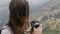 Close-up happy young journalist woman with backpack and flying hair taking photos of epic mountains scenery in Sri Lanka