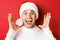 Close-up of happy young man in santa hat, making big christmas announcement, smiling amazed, standing over red