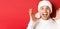 Close-up of happy young man in santa hat, making big christmas announcement, smiling amazed, standing over red