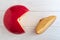 Close up. Head of Dutch cheese Edam and sliced piece on white wooden background