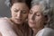 Close up head shot caring mature mother hugging daughter