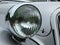 Close up of the headlamp of an elegant silver colored stylish 1930s vintage automobile