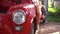 Close up of headlight of old red classic car. Headlight have chrome polished bezel. Turn signal under headlight lamp of