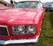 Close up, headlights of a shiny red classic car with focus on headlights and hood