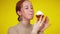 Close-up headshot of charming redhead woman with green eyes enjoying sweet delicious dessert at yellow background