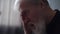 Close-up headshot of gray-haired upset depressed mature adult man crying alone at home thinking of loneliness grief.