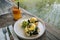 Close up Healthy Breakfast with Bread Toast and Poached Egg with spinach, avocado on wooden table with view on rice field. Orange